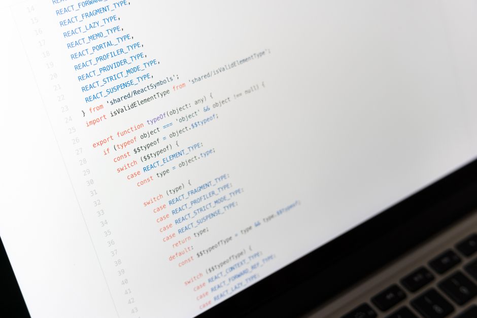 A laptop screen showing a React source-code file with React-specific constant names like REACT_FRAGMENT_TYPE and REACT_LAZY_TYPE in a light editor theme.