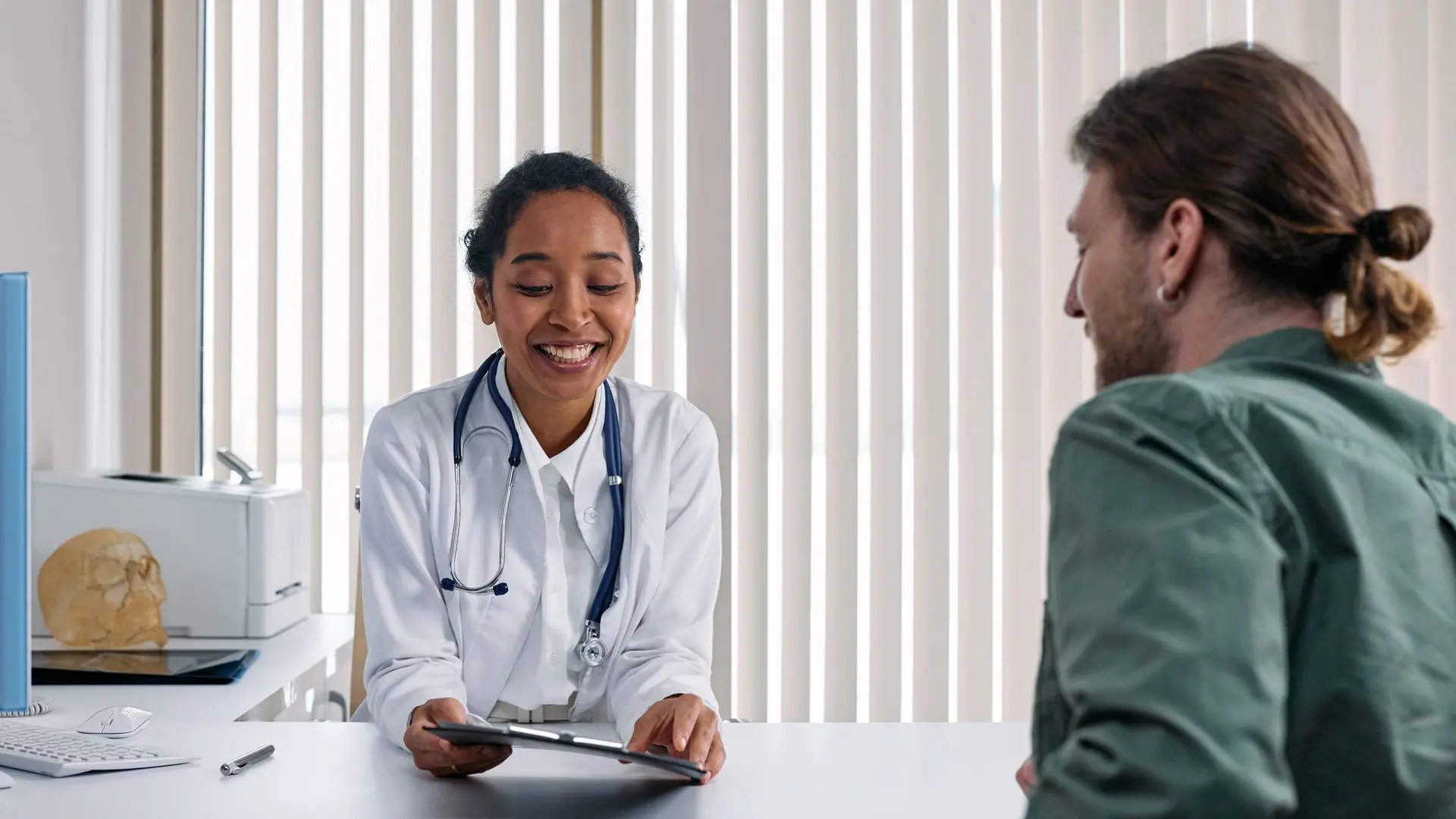 At Riverside Family Practice, Dr. Sarah Bennett shares a treatment plan with a patient across the desk in a bright modern exam room.