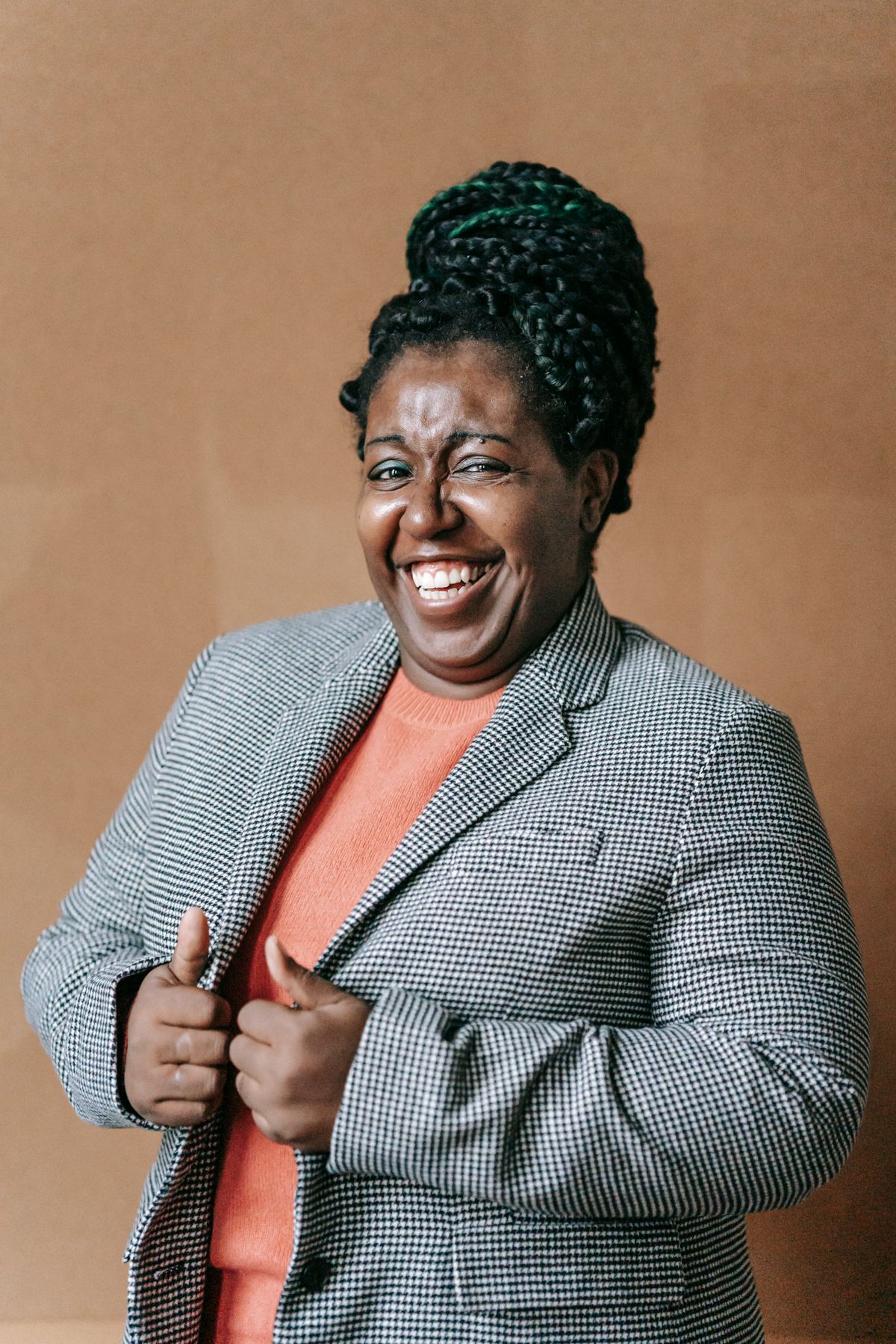 A professional Black woman in a houndstooth blazer laughing warmly against an earth-toned background, used as the Executive Director portrait.