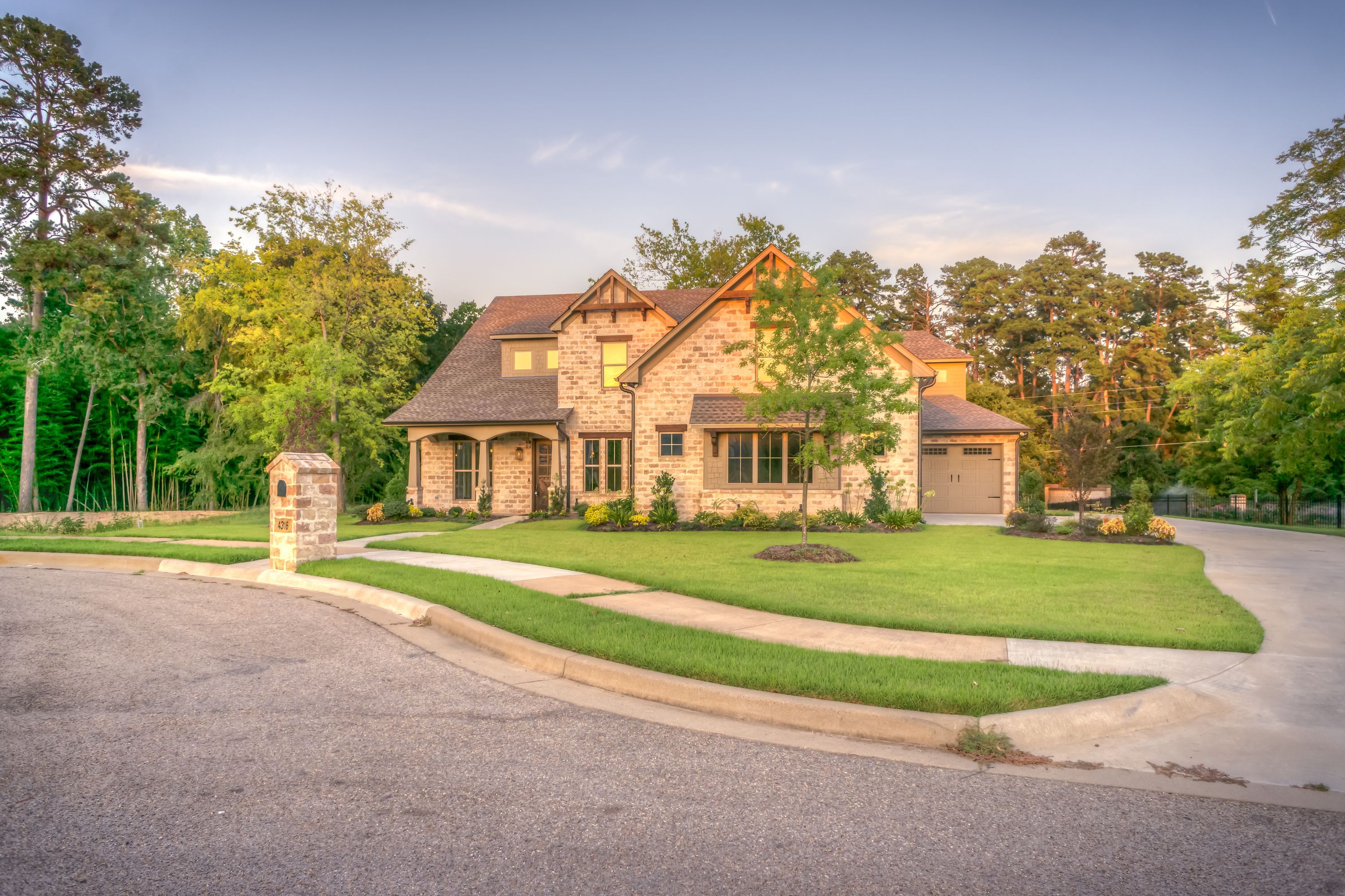 A well-maintained upscale residential property with clean landscaping, photographed in warm daylight.