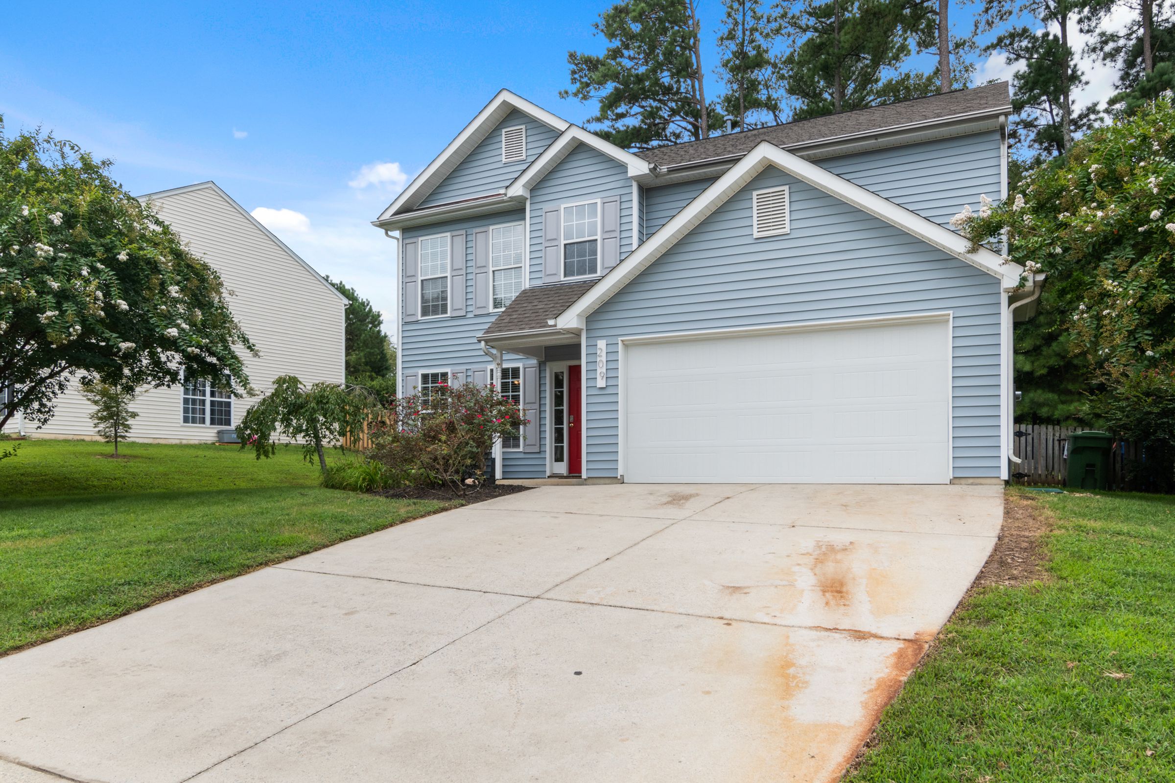 A residential single-family home exterior with a porch and landscaped yard.