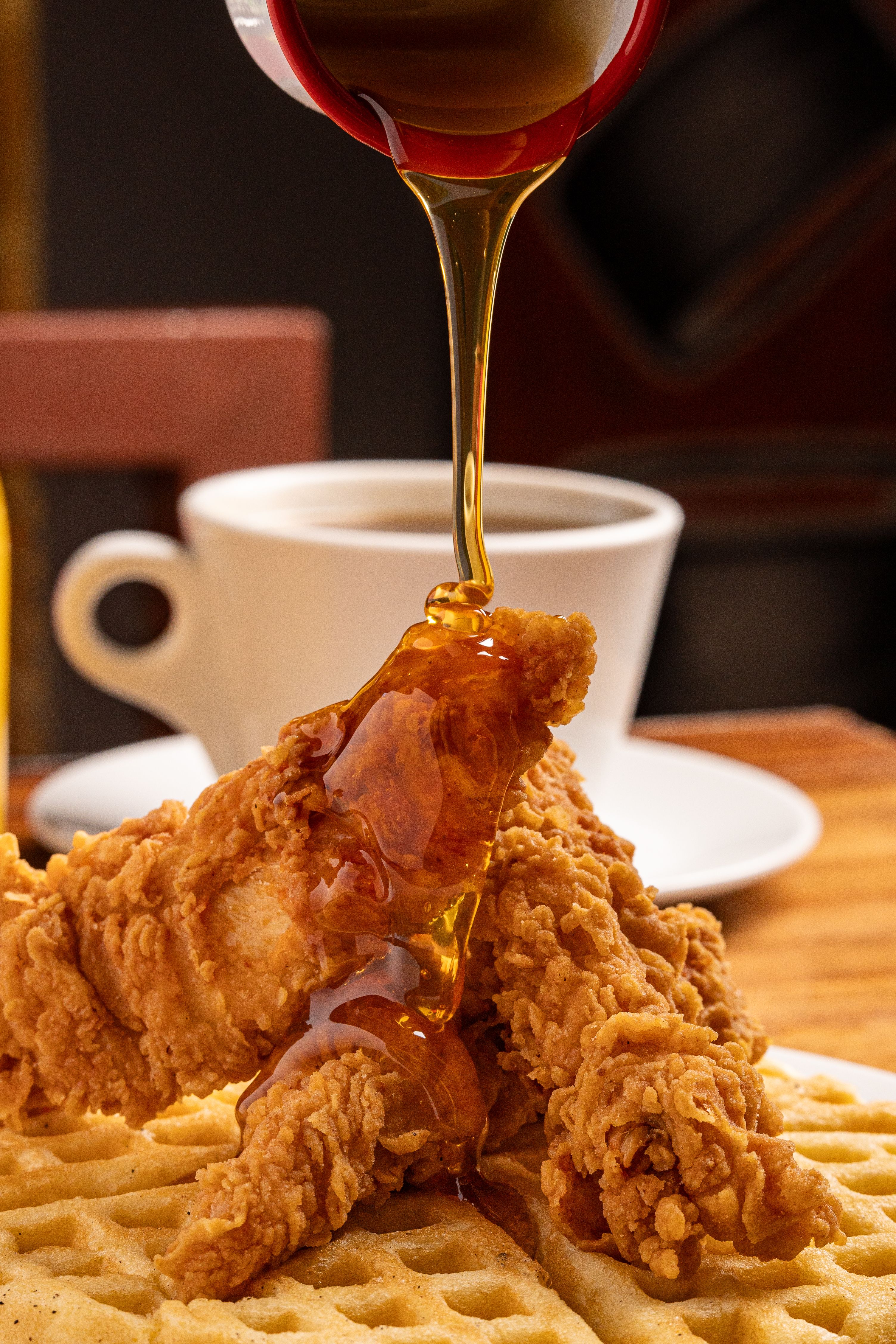 Buttermilk fried chicken on a Belgian waffle with hot maple syrup being drizzled on top at The Steel Hearth.
