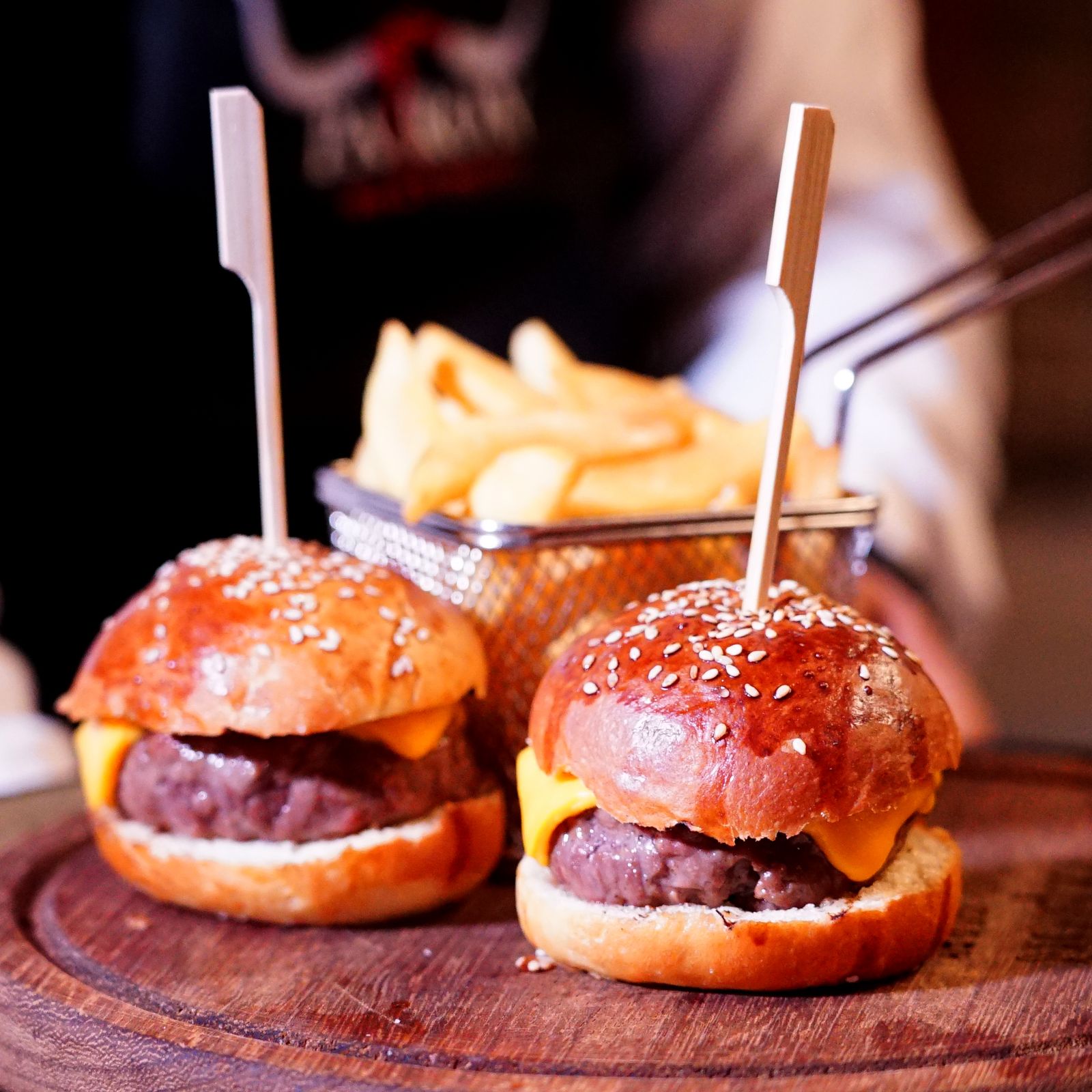 Two cheeseburger sliders with fries on a wooden board at The Steel Hearth.