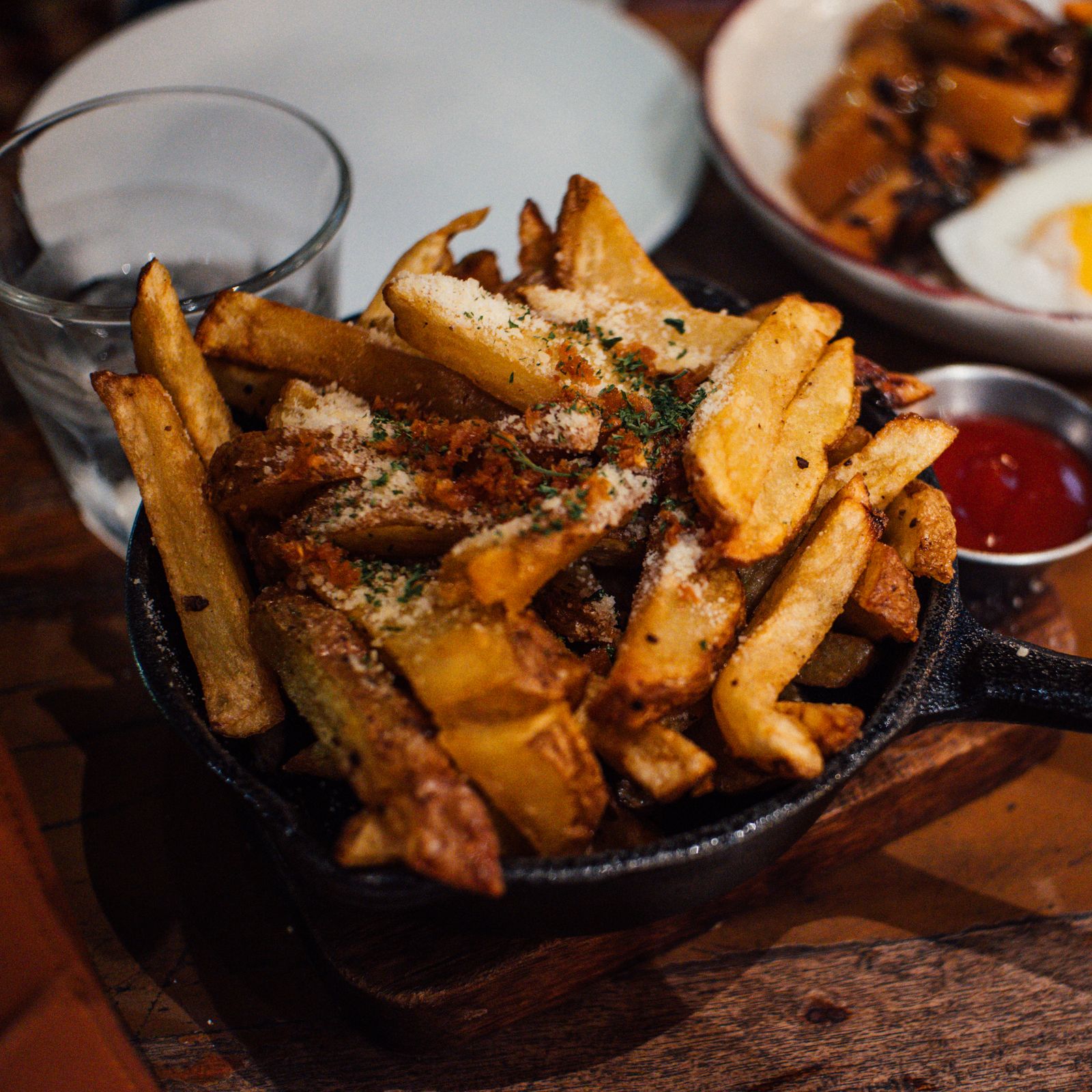 A cast-iron skillet of parmesan-and-paprika fries at The Steel Hearth, with a side of ketchup.