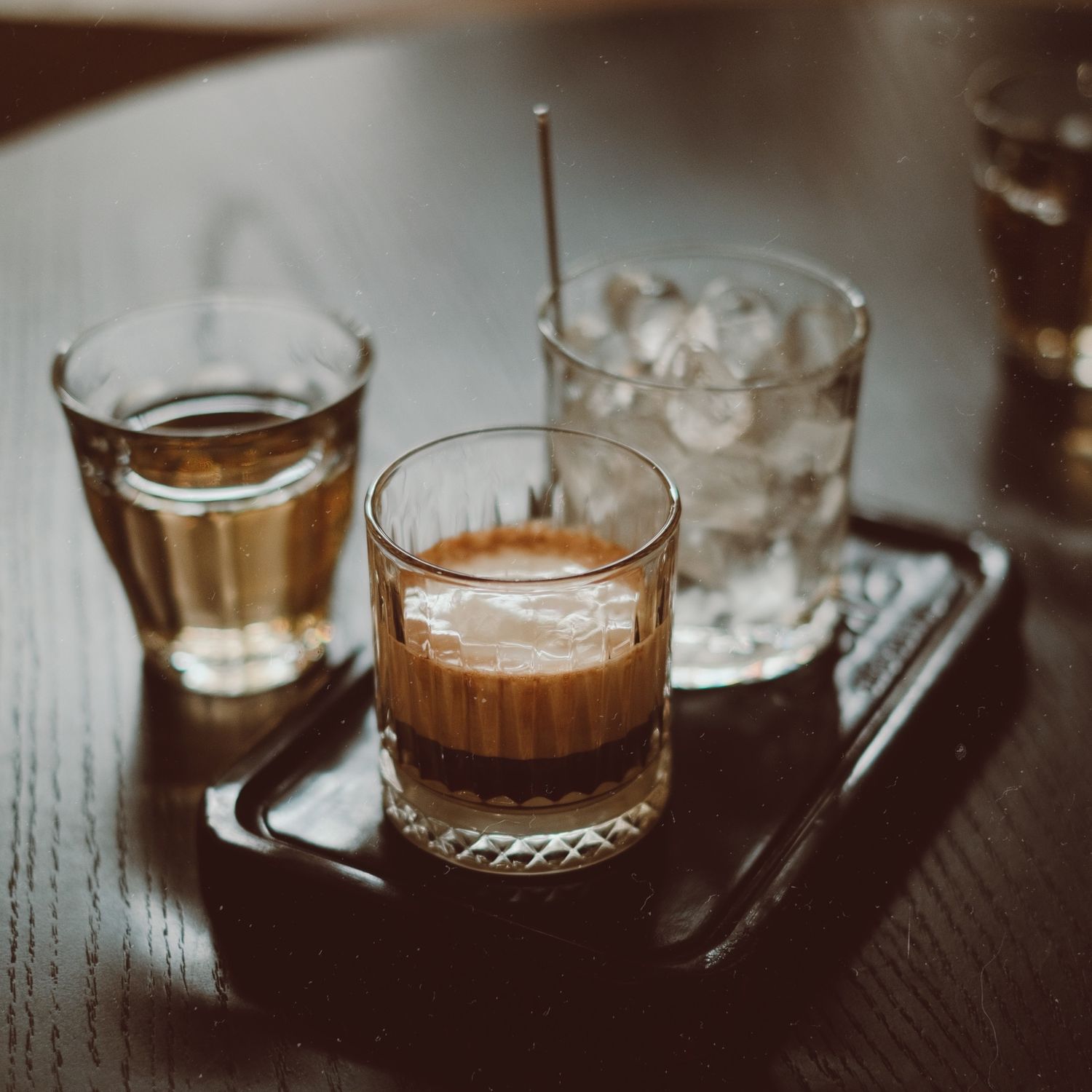 A craft beer flight, four small glasses on a wooden paddle.