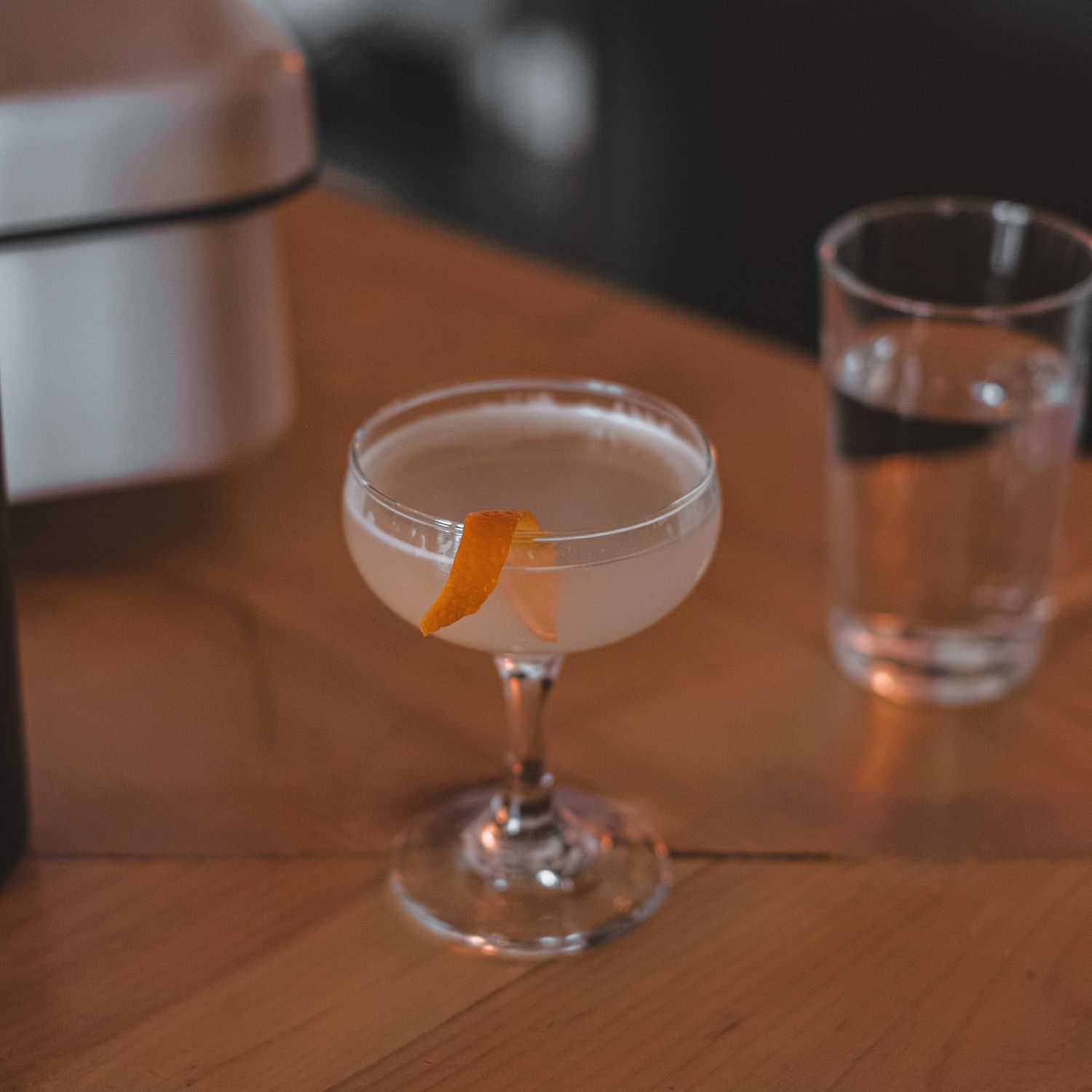 A signature cocktail with a twist of orange peel in a coupe glass.