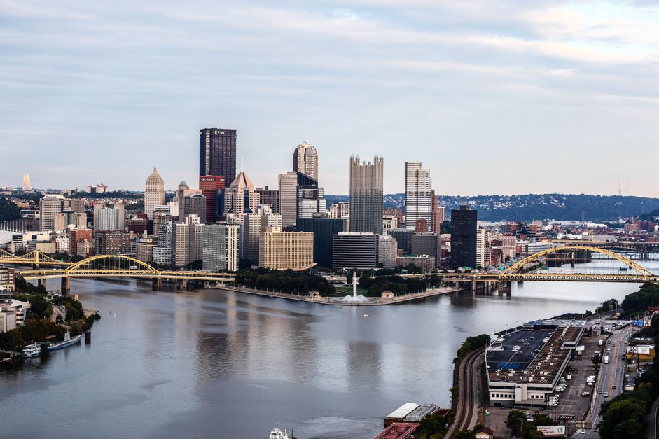 A classic view of the downtown Pittsburgh skyline from the Mt. Washington overlook, showing the UPMC Tower, PPG Place, the Grant Street buildings, and the confluence of the three rivers with the Point State Park fountain.