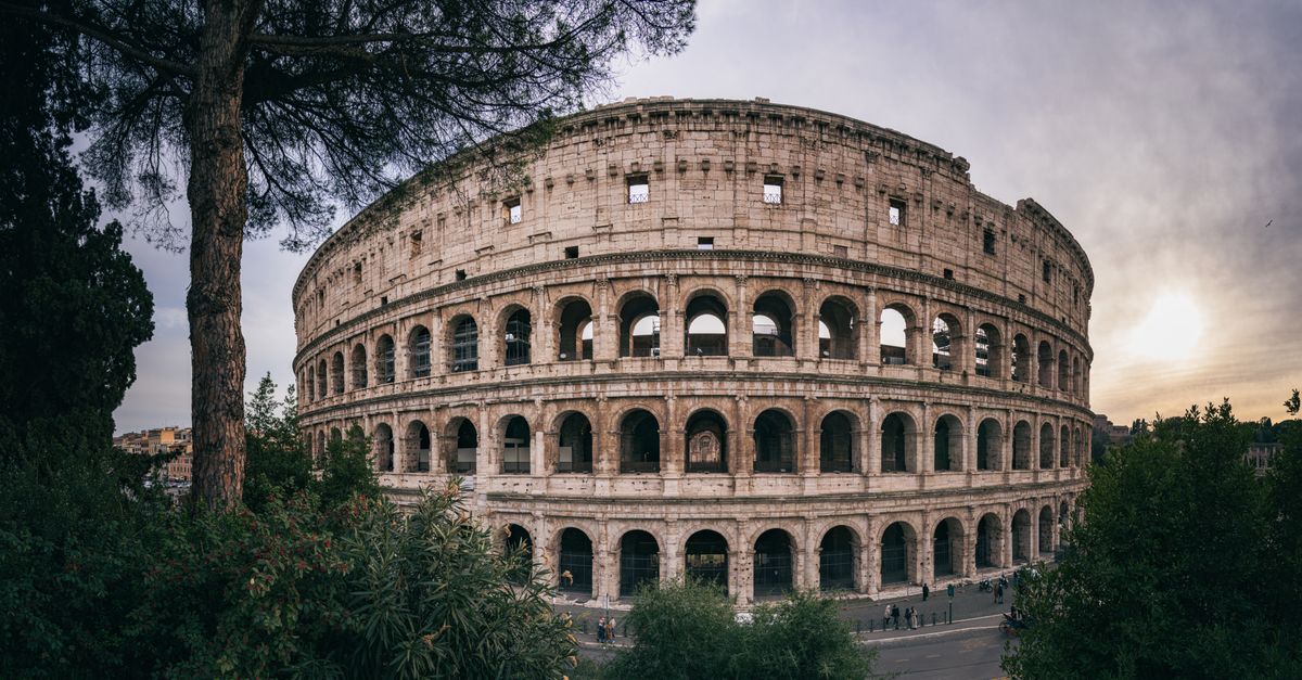 The Colosseum in Rome at sunset, ancient stone arches glowing in warm golden light.